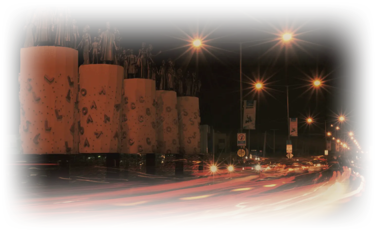 Ikeja after dark, sodium lamps over the monument at Maryland and an hour of traffic drawn as one line