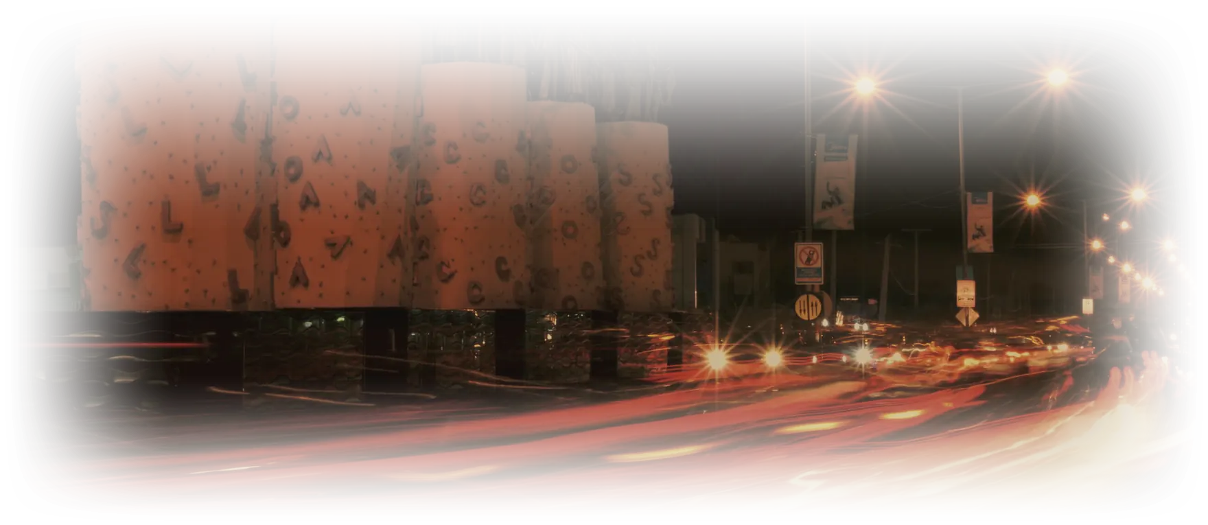 Ikeja after dark, a row of sodium lamps over the road and an hour of traffic drawn as one line